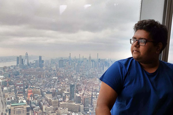 student in tall building looking out window with Boston buildings below